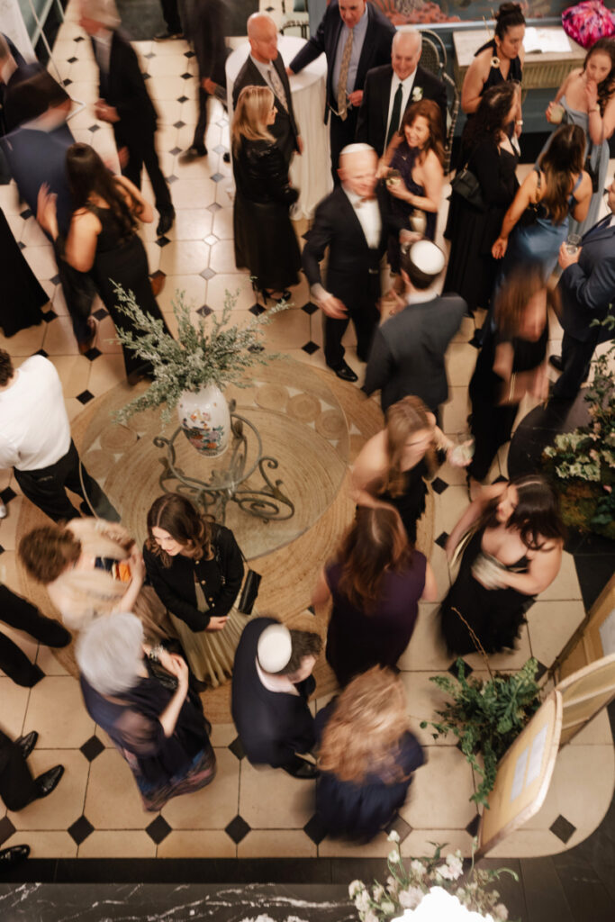 Overhead view of a lively cocktail hour, capturing the energy, movement, and natural flow of guests gathering and connecting
