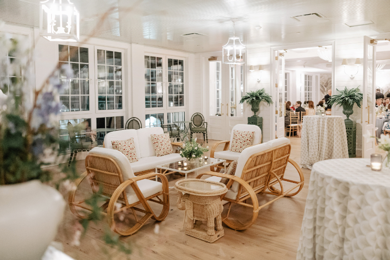 Lounge seating area with woven chairs and soft lighting for relaxed wedding cocktail hour space