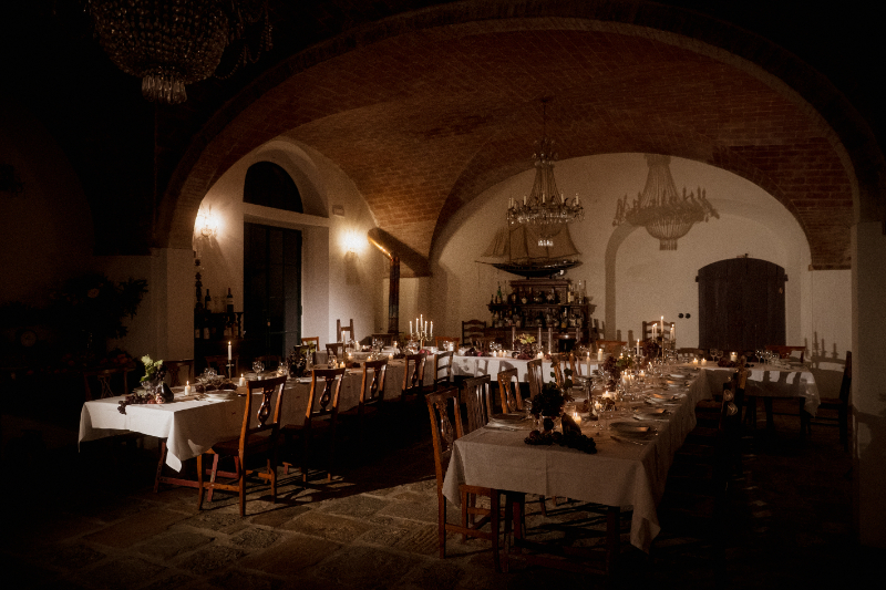 Candlelit reception at Italian wedding destination with long tables, vaulted ceilings, and warm, intimate evening setting