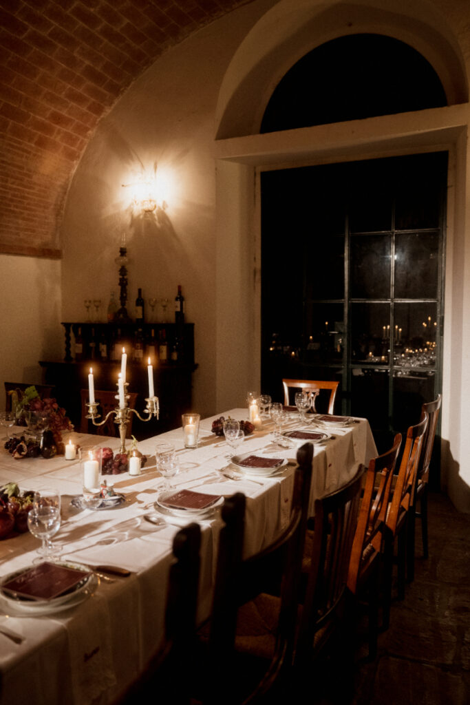 Indoor candlelit dinner setup at Italian wedding destination with long table, glassware, and warm evening light